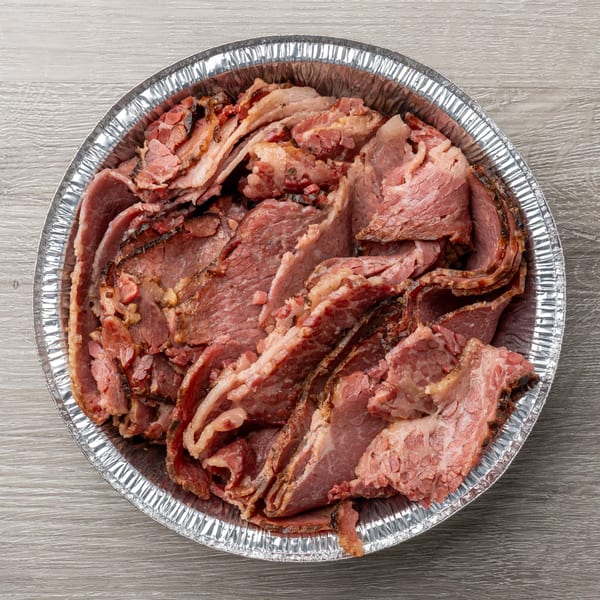 Top-down view of a foil pan filled with thinly sliced, smoked brisket from Hawg Jaw Que & Brew.