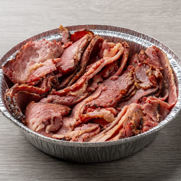 Close-up of a foil pan filled with thinly sliced, juicy Hawg Jaw Que & Brew smoked brisket.
