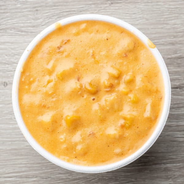 Creamy, orange-colored mac and cheese with visible pasta pieces in a white bowl.