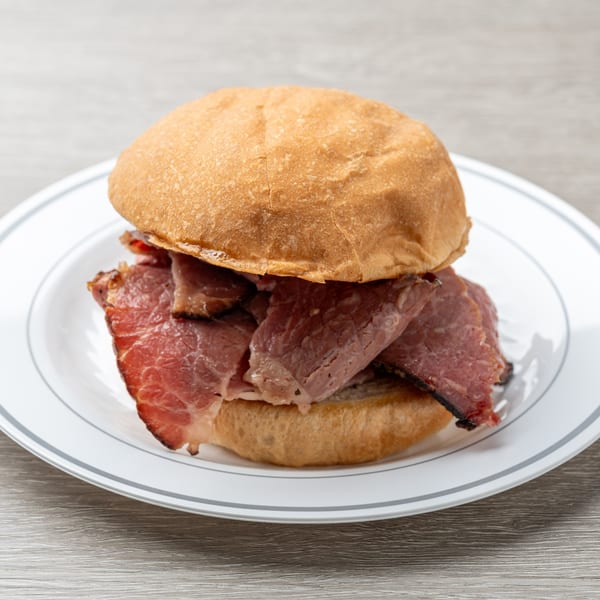 Hawg Jaw Que & Brew's BBQ sandwich with sliced brisket on a white plate.